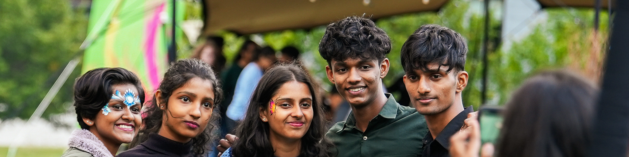 5 people with colourful facepaint getting their photo taken
